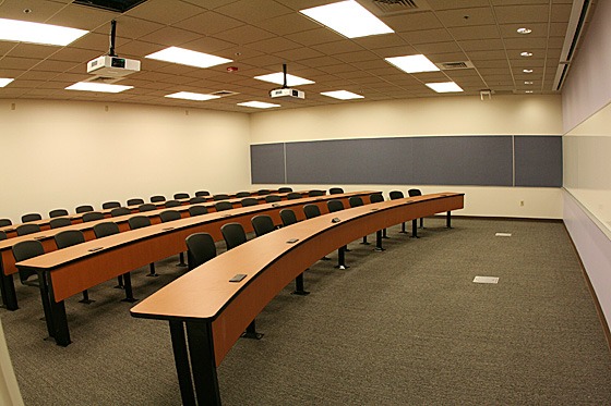 Room 250 in Sutardja Dai Hall. It has three rows of continuous auditorium-style seating with a broad space at front and a blackboard in back.